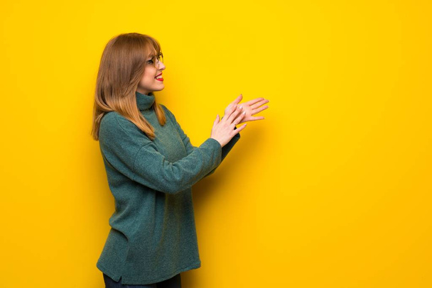 Женщина в очках над желтой стеной аплодирует после презентации на конференции
 - Фото, изображение
