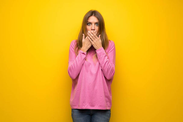 Femme avec pull rose sur le mur jaune couvrant la bouche avec les mains pour dire quelque chose d'inapproprié
 - Photo, image