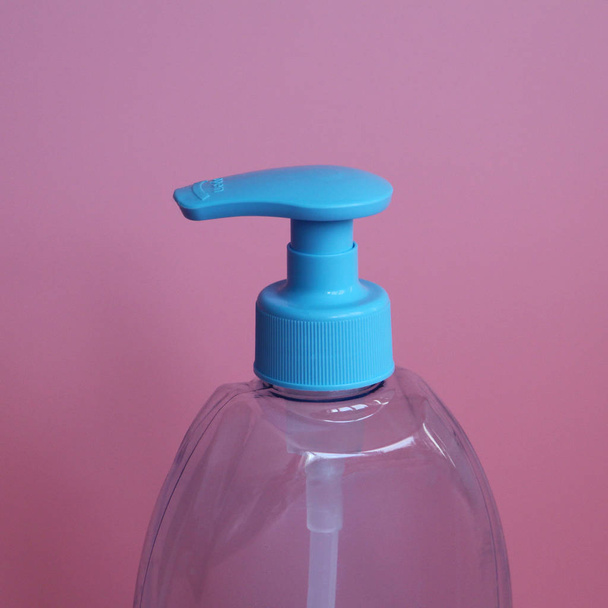 One blue bottle on a pink background. Bottle for cosmetics with dispenser. - Foto, Imagen