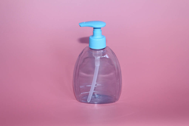 One blue bottle on a pink background. Bottle for cosmetics with dispenser. - Fotoğraf, Görsel