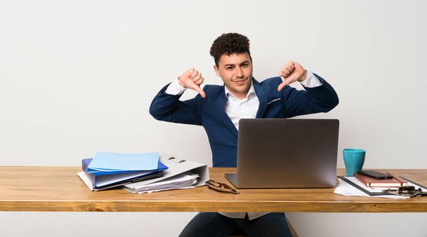 Üzleti ember egy irodában mutató hüvelykujját lefelé - Fotó, kép