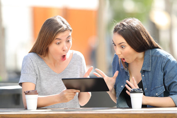Two amazed friends watching media in a tablet - Photo, image