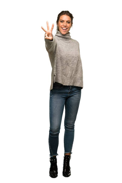 A full-length shot of a Blonde woman with turtleneck happy and counting three with fingers over isolated white background - Foto, immagini