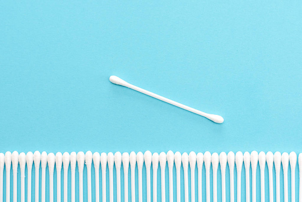 White cotton buds lie in a row on a blue background. - Photo, Image