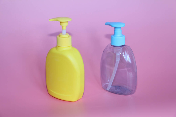 Two plastic bottles on a pink background. Bottles for cosmetics with dispenser. - Foto, Imagem