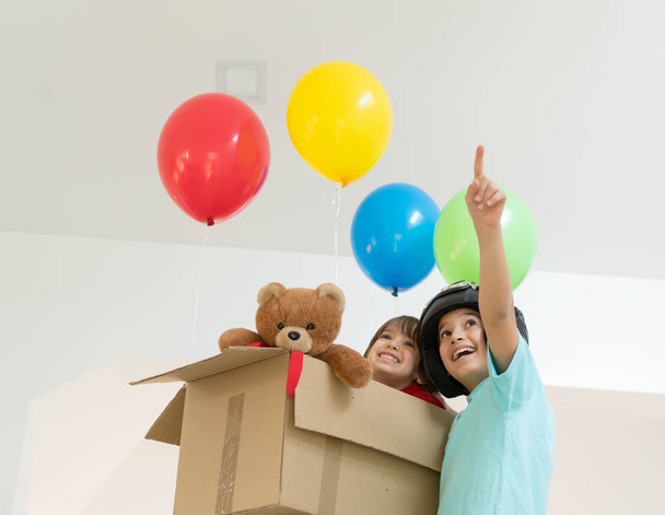Happy brothers playing with balloons and carton box  - Valokuva, kuva