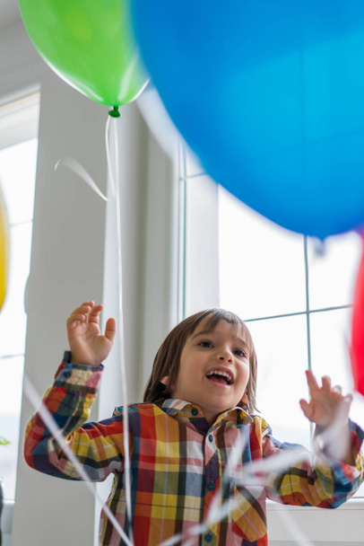 Boy with balloons in front of window  - Фото, зображення