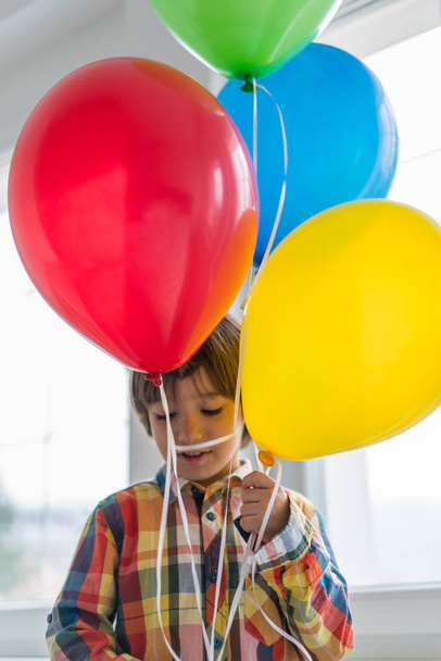 Boy with balloons in front of window  - Fotoğraf, Görsel
