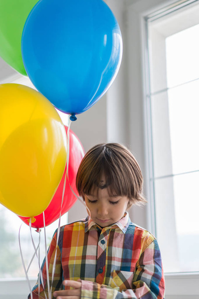 Boy with balloons in front of window  - Valokuva, kuva