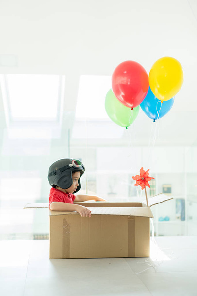 Happy boy sitting in his box imagining him self flying  - Foto, Imagen
