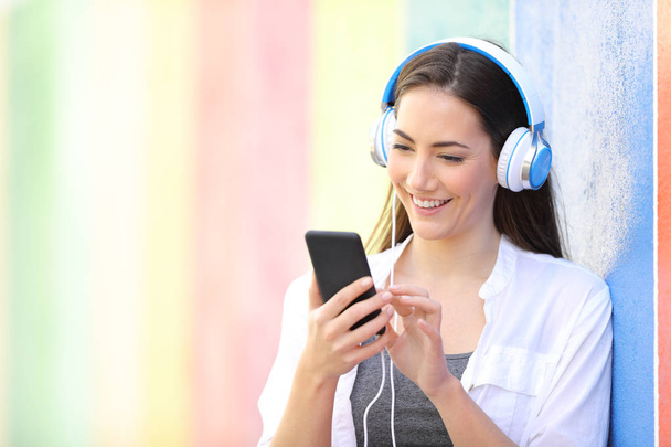 Happy woman listens to music using phone - Fotografie, Obrázek