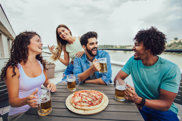 Друзі насолоджуються піцою. Група молодих веселих людей їдять пі
 - Фото, зображення