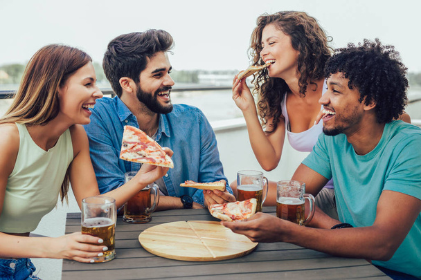 Kamarádi požívající pizzu. Skupina mladých veselých lidí, kteří jedí PI - Fotografie, Obrázek