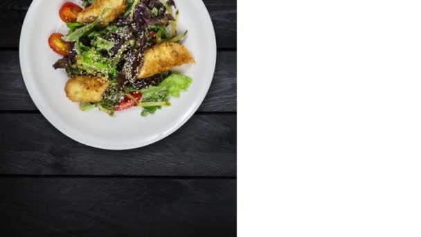 Salat mit Lachs in Semmelbröseln mit Salat und Sesam. dreht sich auf schwarzem Holzhintergrund. quadratisches Layout für soziale Netzwerke und Kopierplatz für Ihren Text. - Filmmaterial, Video