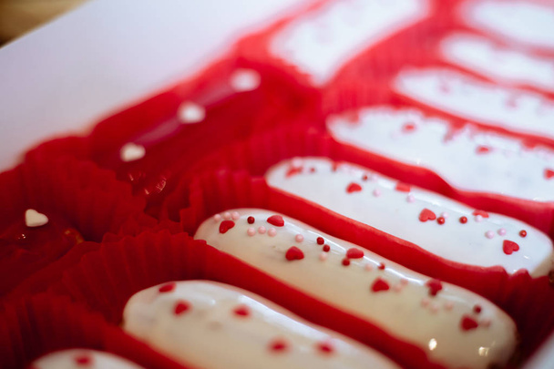 Заварной пирог с белым кремом и красными сердцами в красной бумажной плесени
 - Фото, изображение