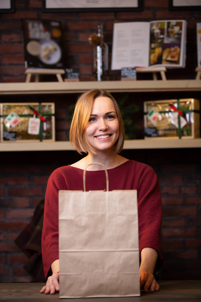 Foto van jonge blonde verkoper met papieren zak - Foto, afbeelding