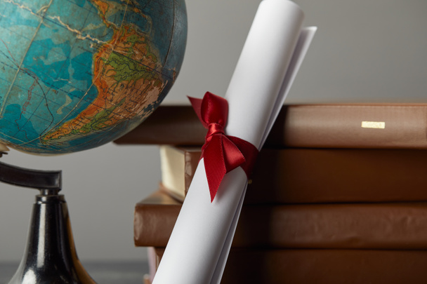 Libri marroni, globo e diploma con nastro rosso su grigio
 - Foto, immagini