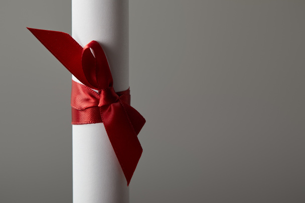Close up view of diploma with red ribbon isolated on grey - Foto, Imagen