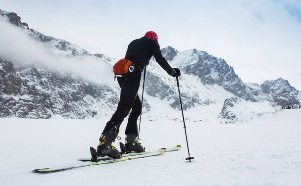 Esquí de montaña de montaña caminando por una cresta nevada con esquís en la mochila. En el fondo el cielo azul y el sol brillante y Zebru, Ortler en Tirol del Sur, Italia. Aventura invierno deporte extremo
. - Foto, Imagen