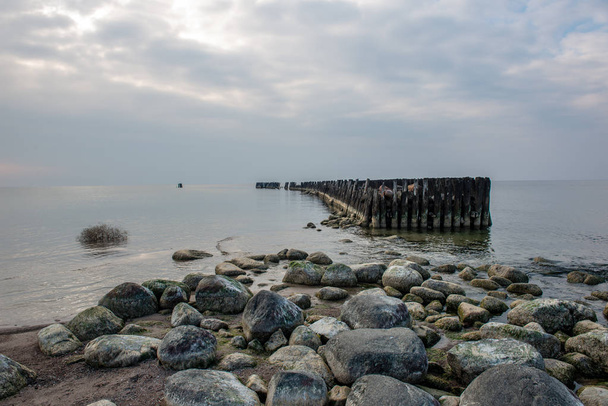 praia de mar calmo no verão com grandes rochas e postes de madeira de
  - Foto, Imagem