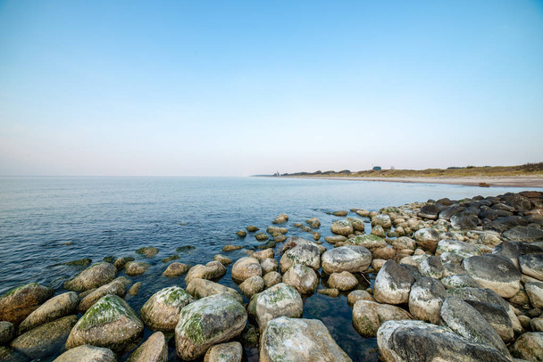 спокійний морський пляж влітку з великими скелями і дерев'яними стовпами з
  - Фото, зображення