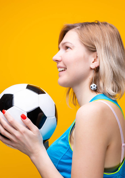 Фото блондинки з футбольним м'ячем на жовтому фоні
 - Фото, зображення