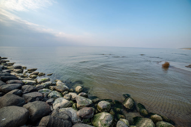 ruhiger Meeresstrand im Sommer mit großen Felsen und Holzpfählen von  - Foto, Bild