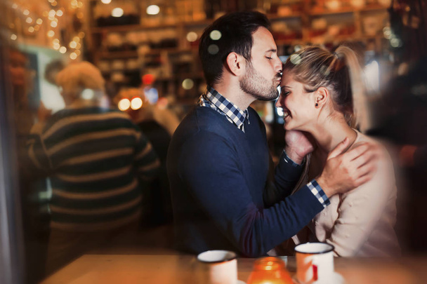 Happy couple kissing at bar and having date - Фото, зображення