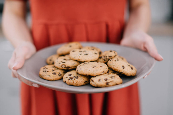 Woman holding plate with fresh cookies in kitchen - Foto, Imagem
