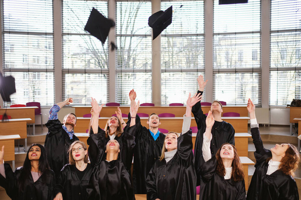 Multi grupo étnico de estudiantes graduados lanzando sombreros
 - Foto, imagen