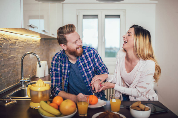glückliches Paar macht Orangensaft in der Morgenküche und mit einem g - Foto, Bild