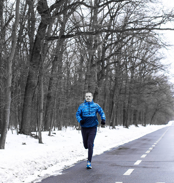 Чоловік біжить на трасі біля зимового лісу вранці
 - Фото, зображення