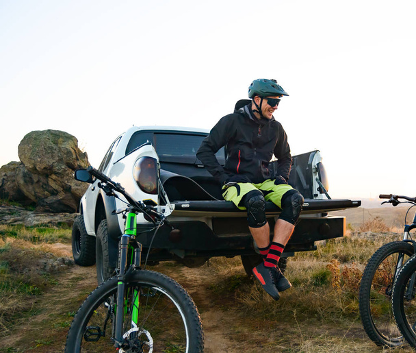 Cyclist on Pickup Off Road Truck Resting after Bike Riding in the Mountains and Talking with Friends - 写真・画像