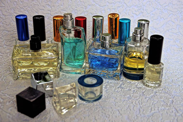 Цветные стеклянные бутылки с духами на сером столе
 - Фото, изображение