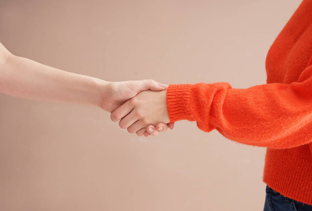 Friends shaking hands on color background - Photo, Image