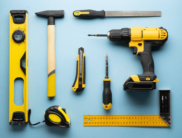 Creative provocation: a flat layout of yellow hand tools on a blue background. - Фото, зображення