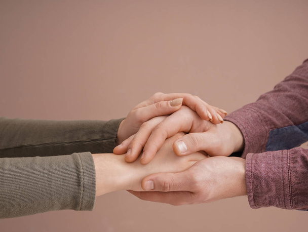 Молода пара тримає руки разом на кольоровому фоні
 - Фото, зображення
