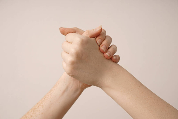 Kobiety, trzymając się za ręce na jasnym tle - Zdjęcie, obraz