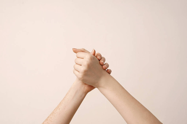 Women holding hands on light background - Photo, Image