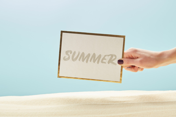 cropped view of woman holding card with summer lettering in hand isolated on blue - Photo, image