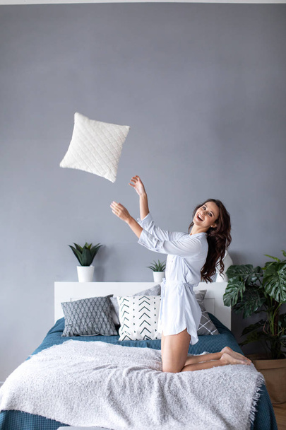 Beautiful cheerful woman with throws a pillow. - Foto, Bild