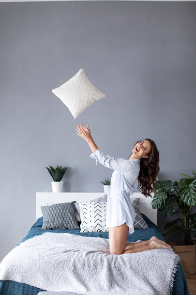 Beautiful cheerful woman with throws a pillow. - Zdjęcie, obraz