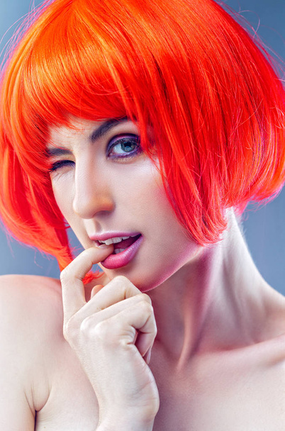 Tricky beauty. Pretty woman in red wig making faces, having fun. - Photo, Image