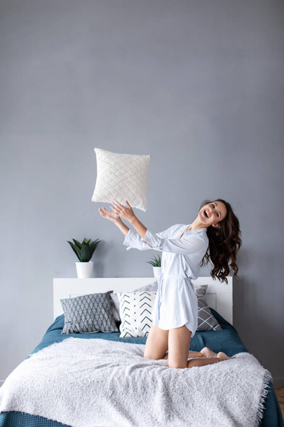 Happy woman having fun pillow throws enjoying funny activity on weekend at home.  - Fotó, kép