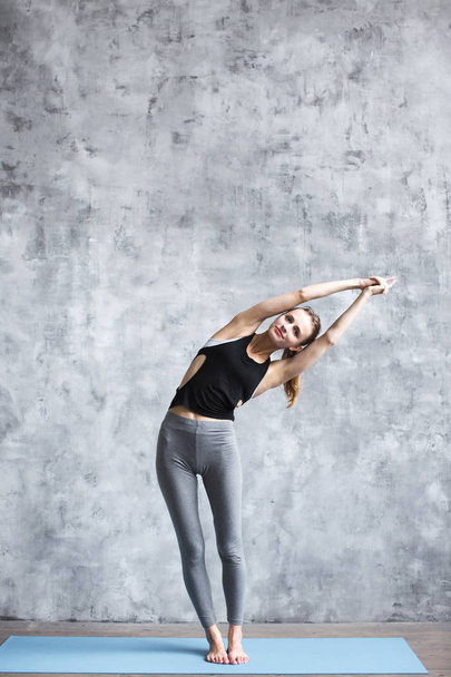Girl doing yoga exercises on a blue yoga mat full-length in the studio. - Foto, immagini