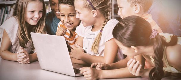 School kids using laptop in library at school - Foto, immagini