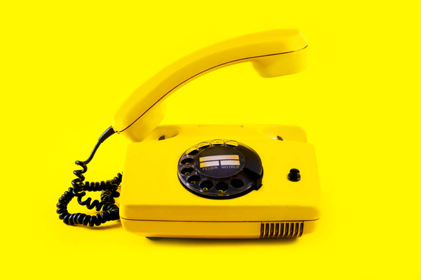 Retro vintage phone handset plastic yellow disko background old style 90 telephone answer call raised - Фото, зображення