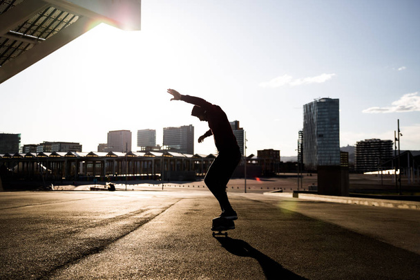male skater skateboarding at urban place with back light - Foto, imagen