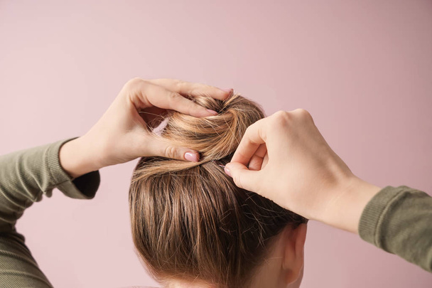 Young woman doing hair on color background - Photo, Image