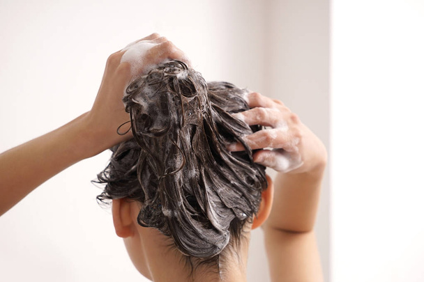 Young woman washing hair in bathroom - Valokuva, kuva